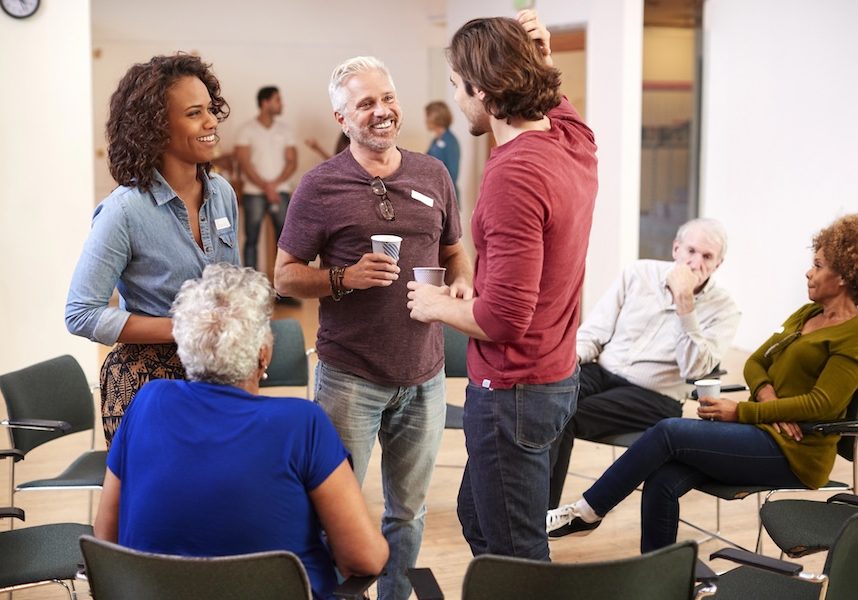 Group Of People Socializing After Meeting In Community Center Group Of People Socializing After Meeting In Community Center